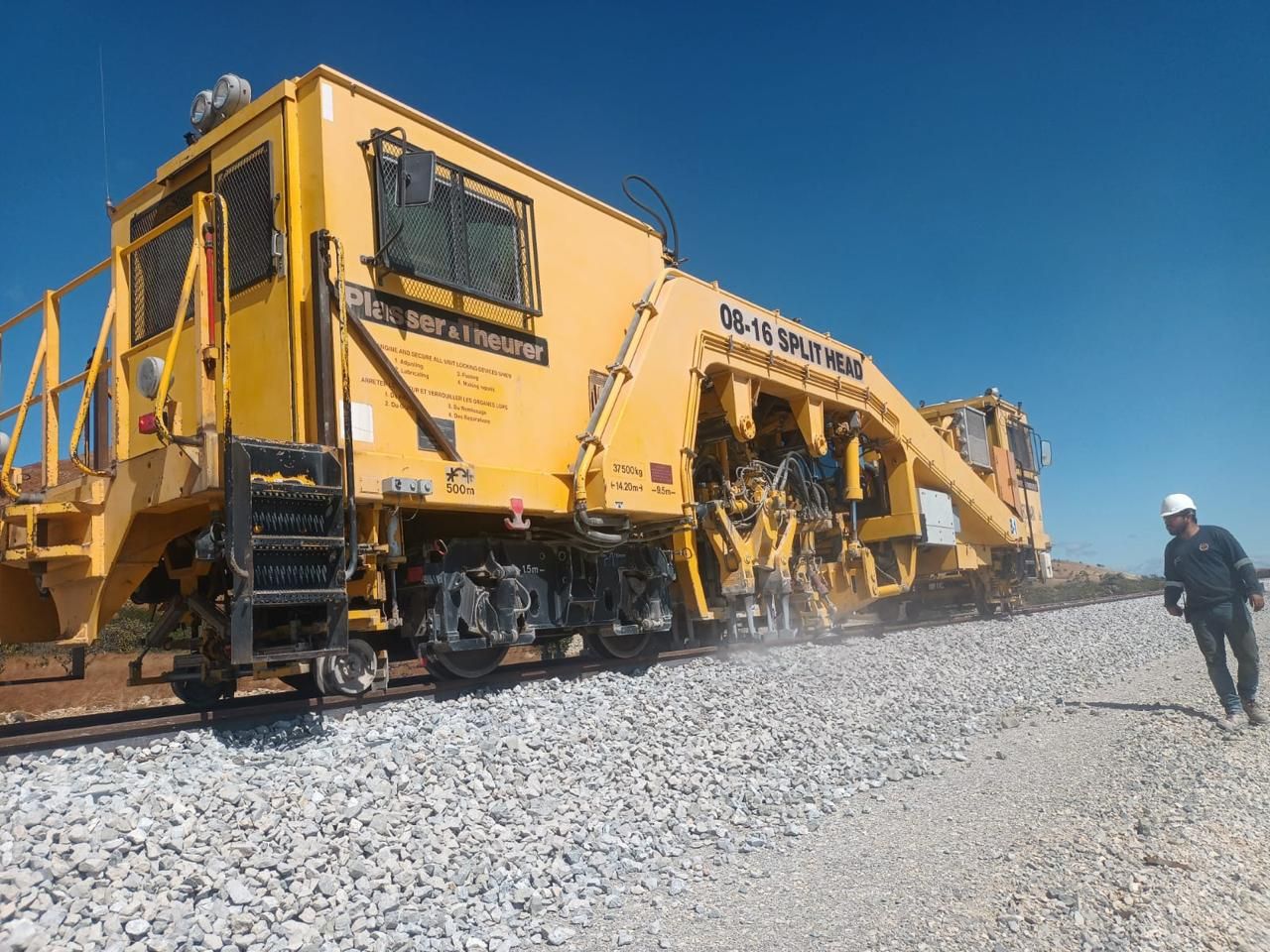 Multicalzadora Plasser & Theurer 08-16 Split Head trabajando, con un técnico a un costado